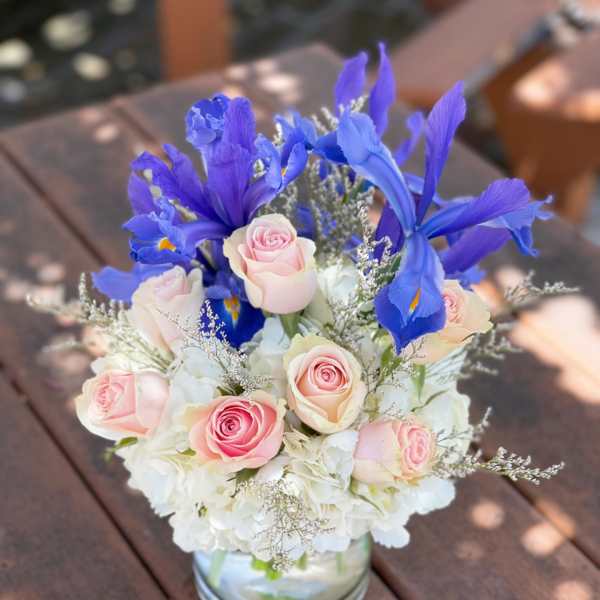 Pink roses and blue irises arranged in a glass vase