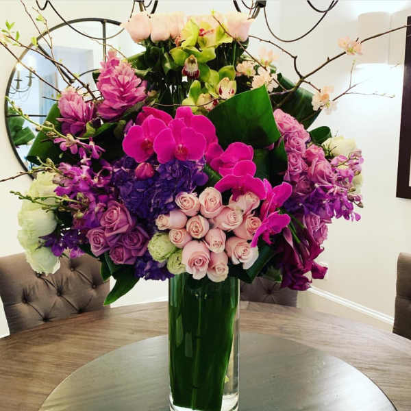 Tall bouquet of pink, purple, and white flowers in a glass vase
