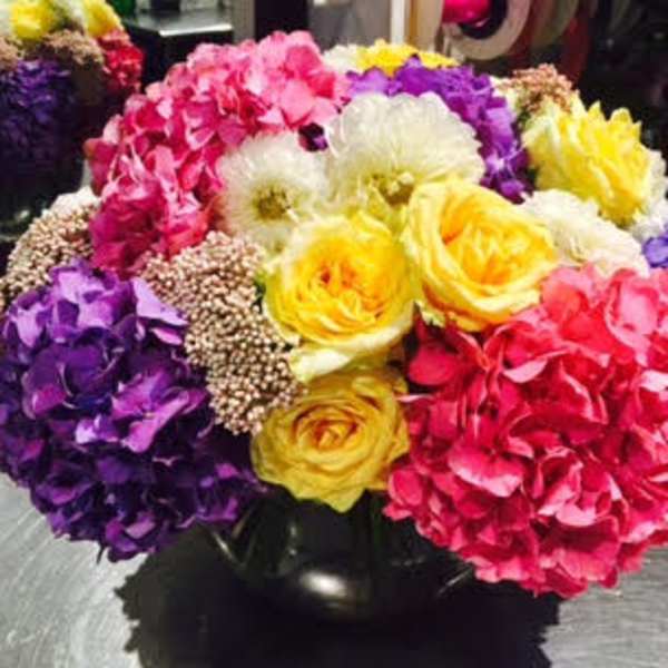 Colorful bouquet of hydrangeas and yellow ranunculus in a black vase