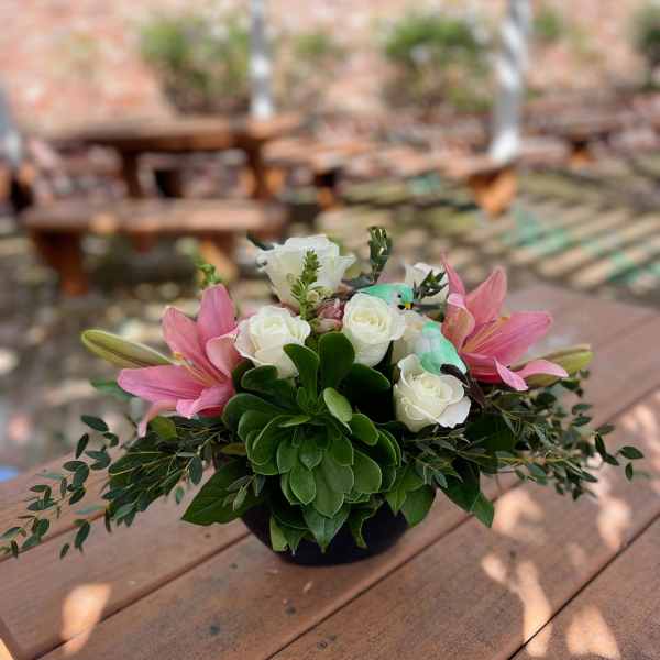 Pink lilies and white roses in a low black container