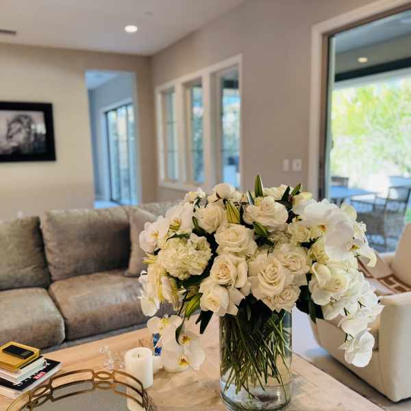 Large white floral arrangement in a clear glass vase on a coffee table