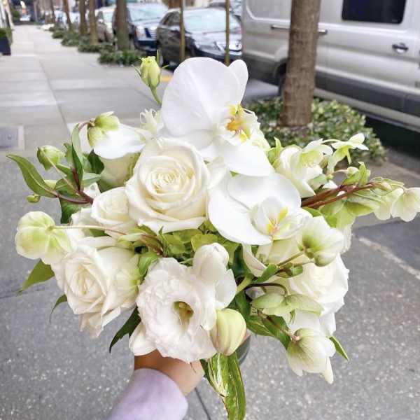 White rose and orchid bouquet held outdoors