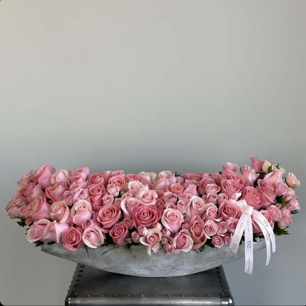 Long low arrangement of pink roses in a gray container