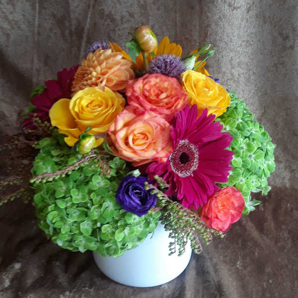 Colorful bouquet in a white vase with roses, gerbera daisies, and hydrangeas