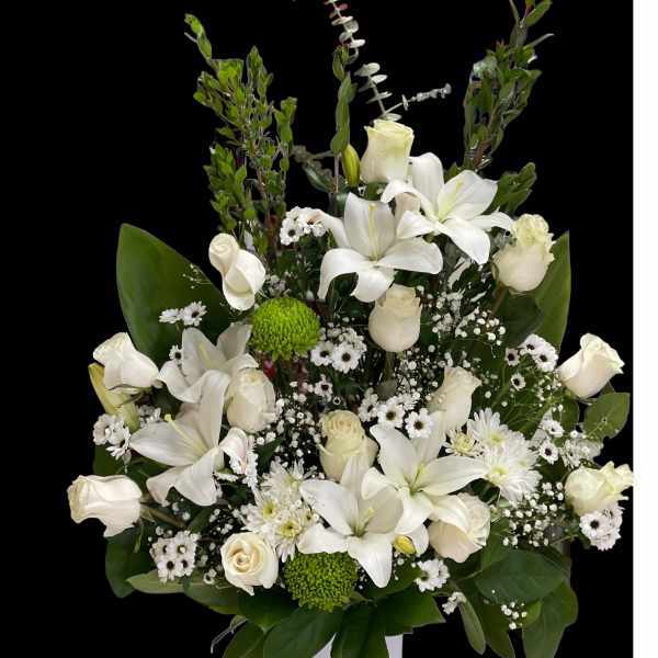 White lilies and roses in a white vase with green accents