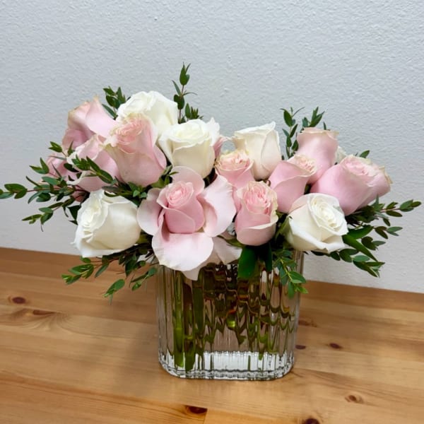 Pink and white roses arranged in a clear glass vase