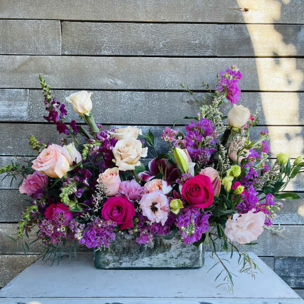 Large mixed bouquet of pink, purple, and white flowers in a rectangular vase