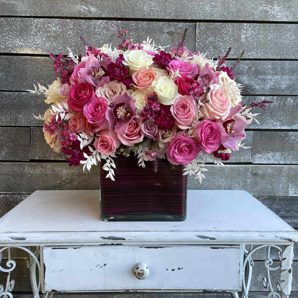 Pink and white rose bouquet in a square glass vase