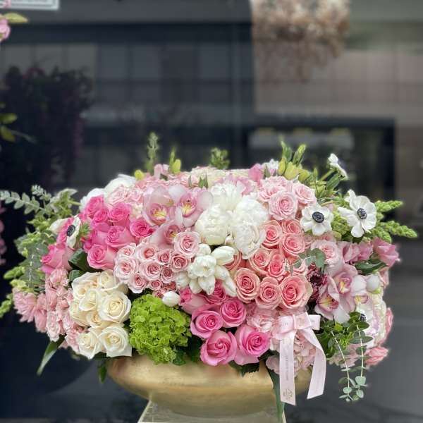 Large pink and white rose arrangement in a gold bowl vase
