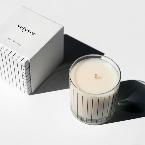 Scented candle in a glass jar beside its white box