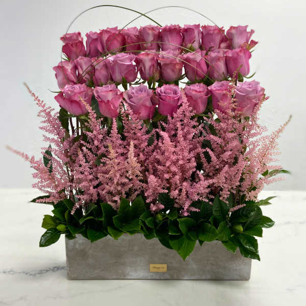 Pink roses arranged in a rectangular gray box with arching wire accents
