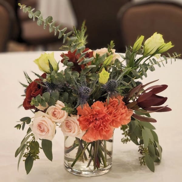Mixed bouquet in a clear glass vase with roses, carnations, and greenery