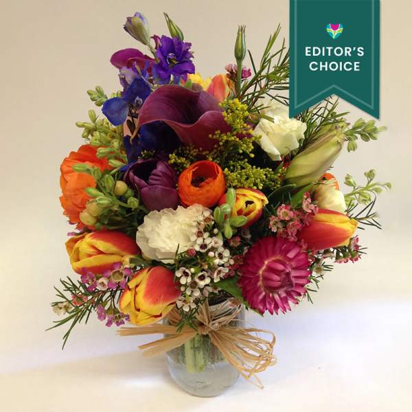 Colorful mixed bouquet in a clear glass vase with a ribbon bow