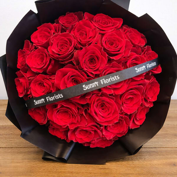 Bouquet of red roses wrapped in black paper with a ribbon
