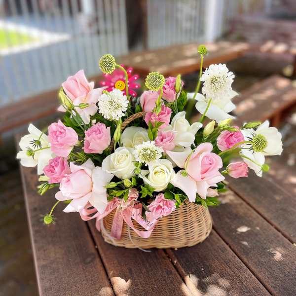 Pink and white flowers arranged in a wicker basket