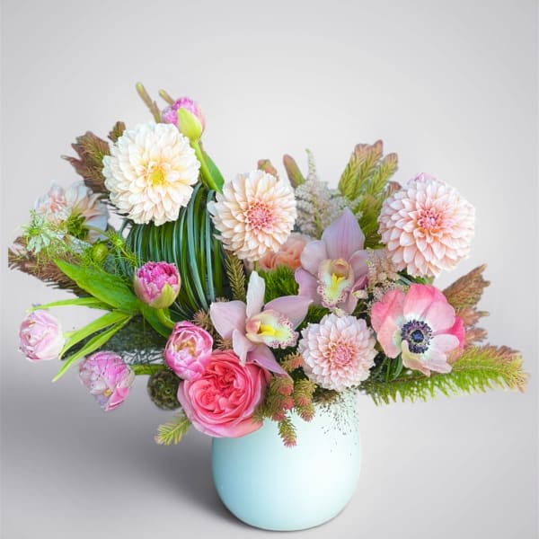 Mixed pastel bouquet in a light blue vase with pink and white blooms