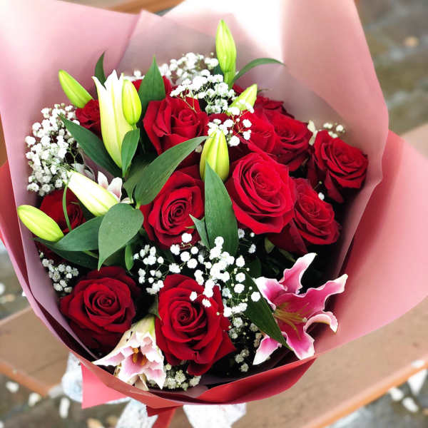 Bouquet of red roses and pink lilies wrapped in pink paper