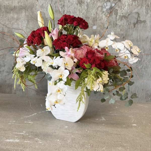 Red roses and white orchids arranged in a white vase