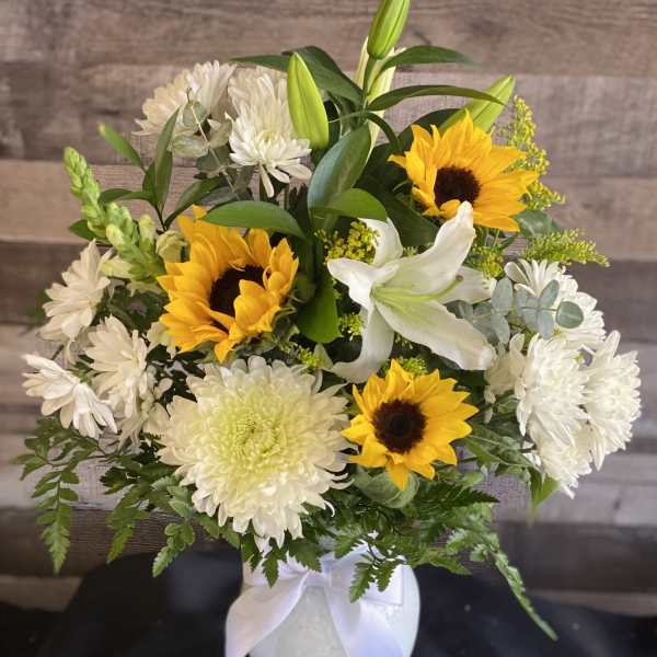 Bouquet of sunflowers, white lilies, and white chrysanthemums in a white vase