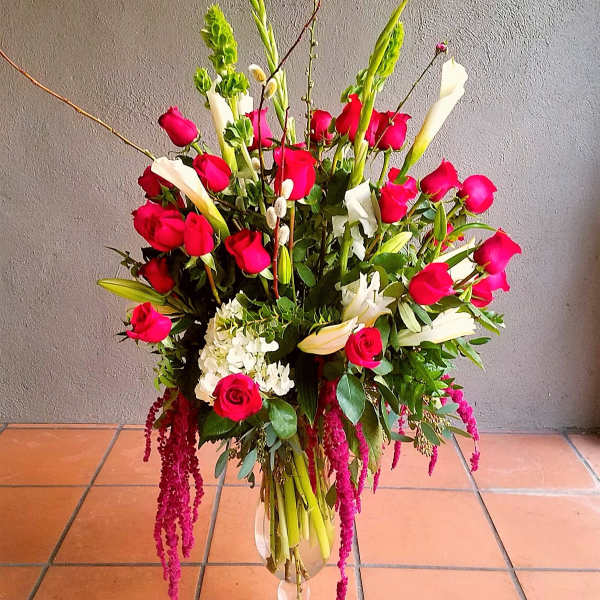 Tall bouquet of red roses, white calla lilies, and lilies in a glass vase