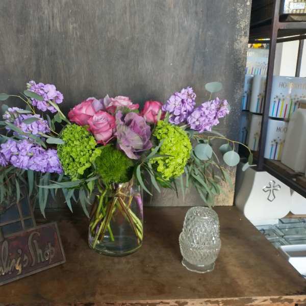 Bouquet of pink roses and purple flowers in a glass vase