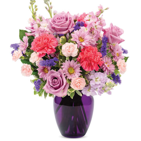 Mixed pink and purple flower arrangement with roses, carnations, and daisies in a deep purple glass vase