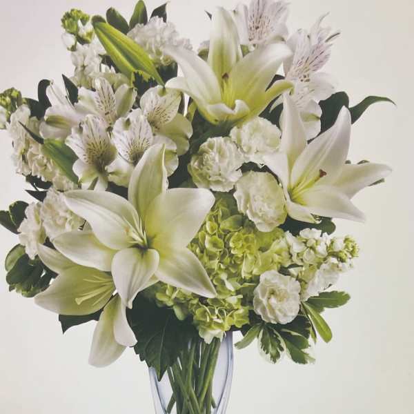 White lilies and green hydrangeas in a clear glass vase