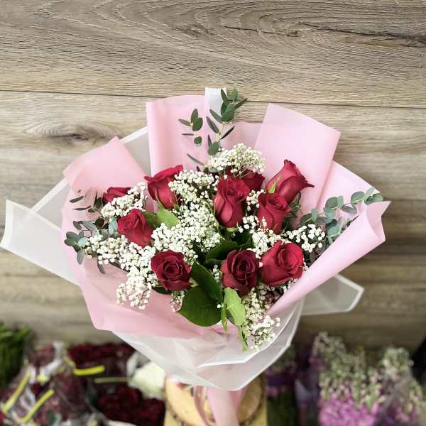 Bouquet of red roses with white baby's breath in pink wrapping