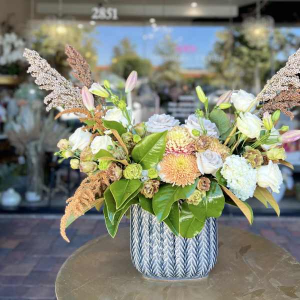 Mixed bouquet in a blue ceramic vase with white and peach blooms