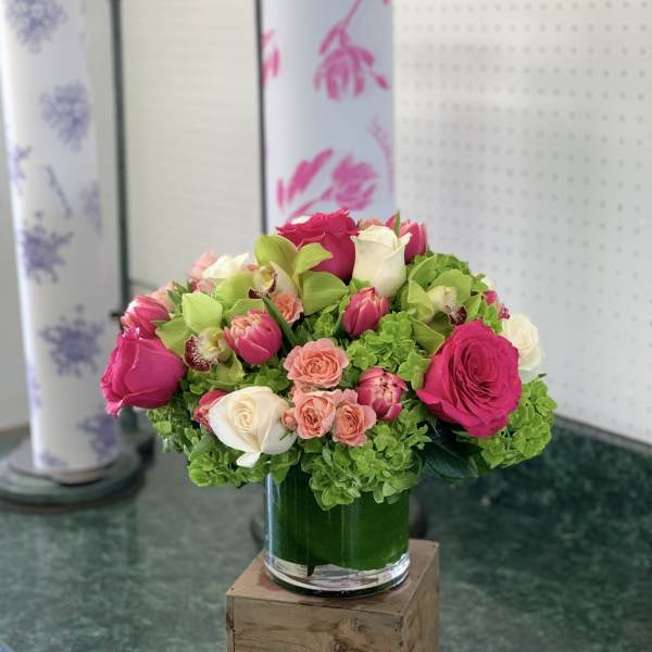 Pink and white roses with green hydrangeas in a glass vase