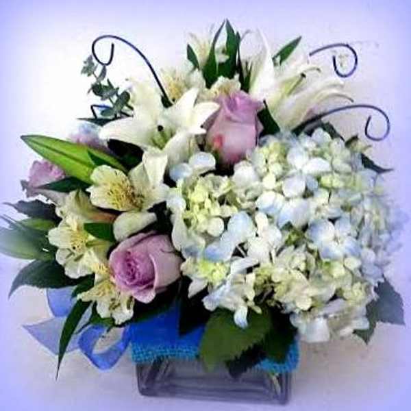Bouquet of white lilies, pink roses, and pale hydrangeas in a vase