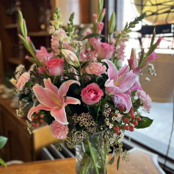 Pink lilies and roses arranged in a glass vase