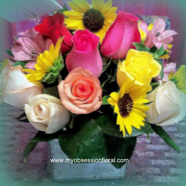 Mixed bouquet of roses and sunflowers in a clear vase