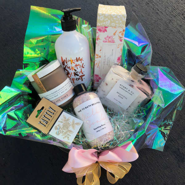 Bath and body gift basket with bottles, jars, and a pink bow
