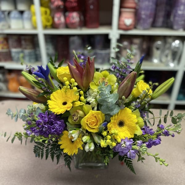 Yellow and purple mixed bouquet in a square glass vase