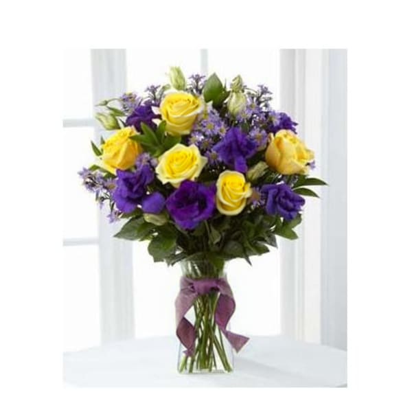 Bouquet of yellow and purple roses in a clear glass vase