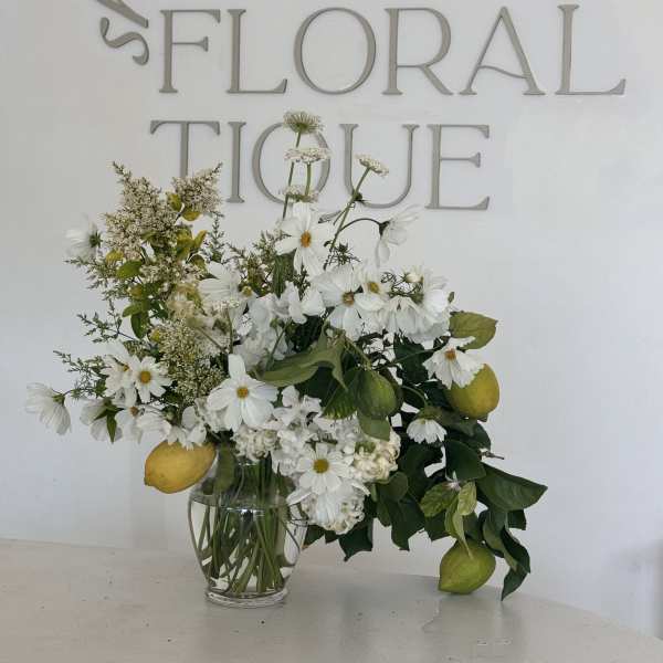 White daisy bouquet with lemons in a clear glass vase