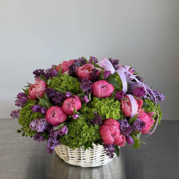 Pink peonies and purple lilacs in a white basket