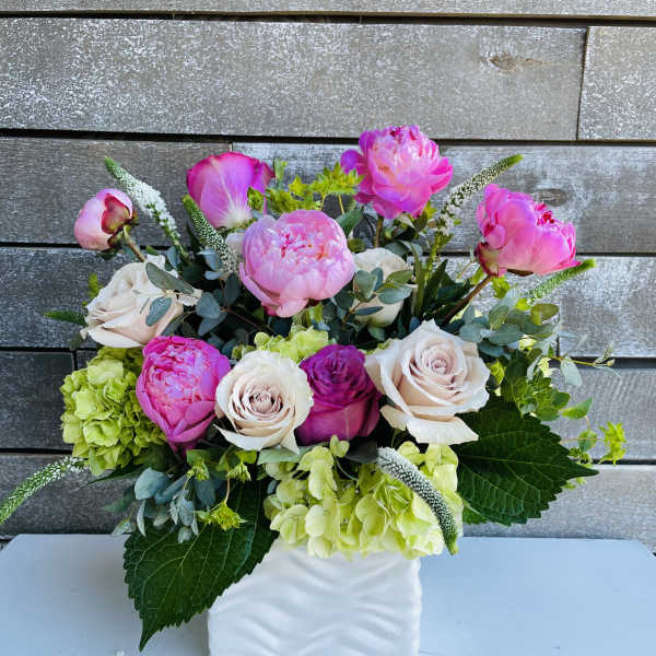 Pink and white flowers arranged in a white square vase