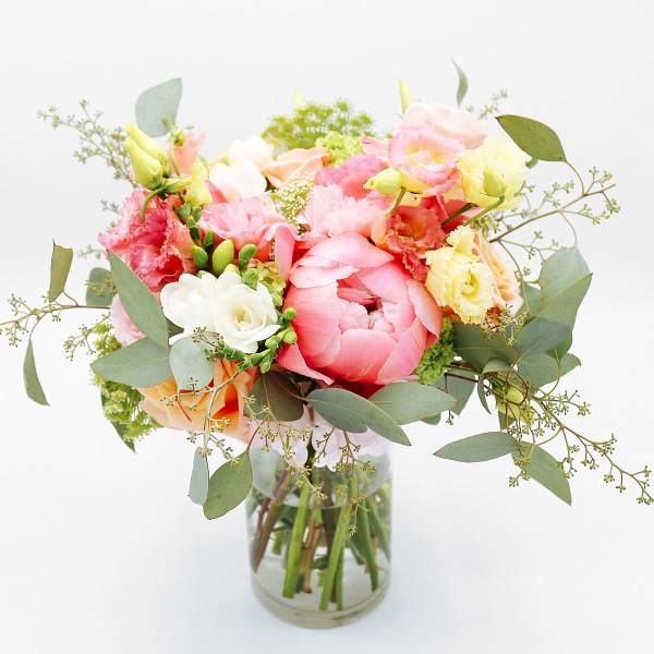 Pastel bouquet of pink peonies and mixed blooms in a clear glass vase