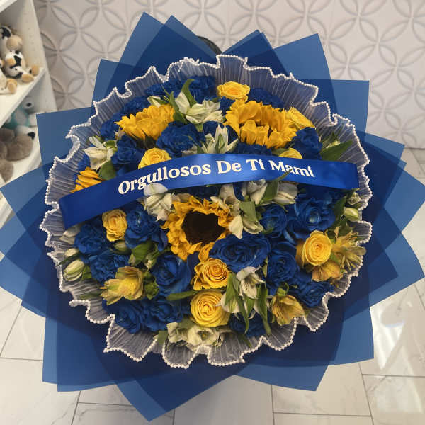Blue and yellow bouquet with a ribbon reading "Orgullosos De Ti Mami"