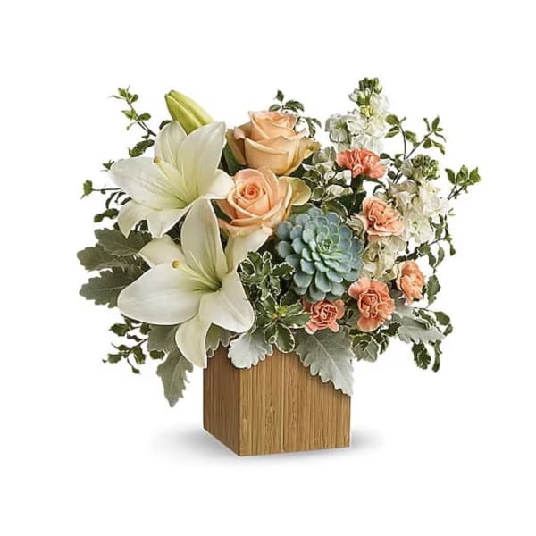 Floral arrangement with white lilies, peach roses, and a blue succulent in a wooden cube vase