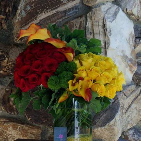Bouquet of red and yellow roses with calla lilies in a glass vase