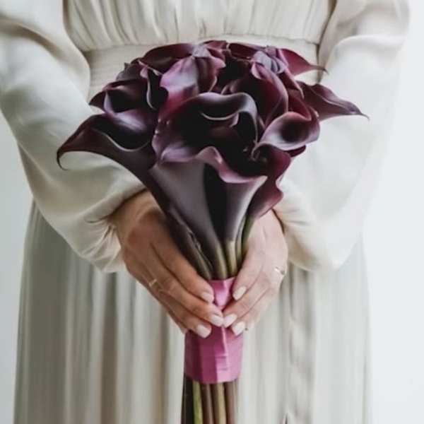 Bouquet of dark purple calla lilies held in both hands