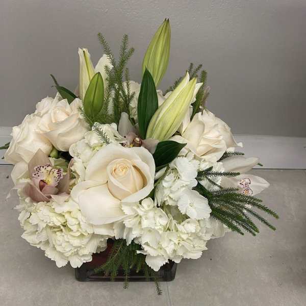 White roses and lilies arranged in a low square vase