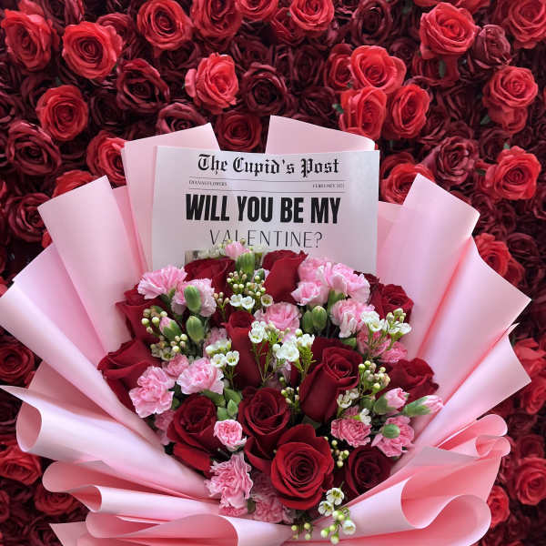 Bouquet of red roses and pink carnations wrapped in pink paper