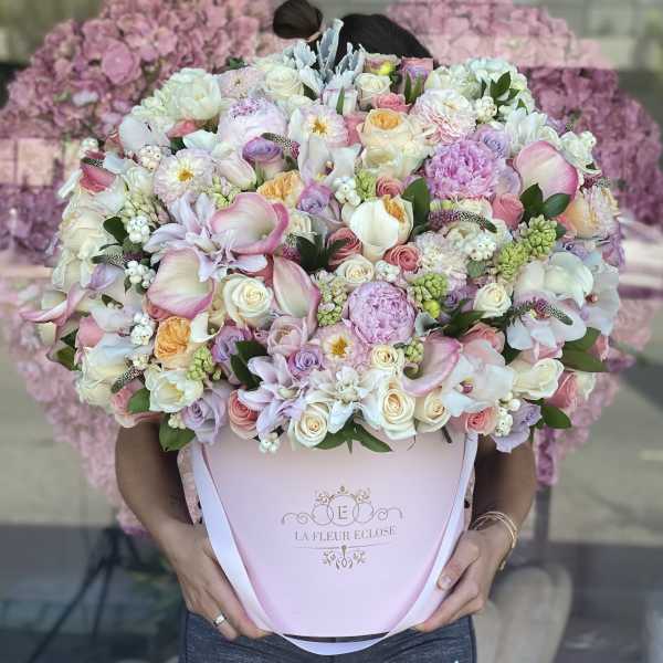 Large pastel bouquet in a pink box held by a person