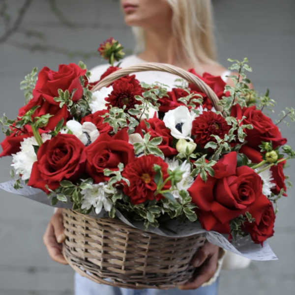 Basket of red roses and white flowers held by a woman