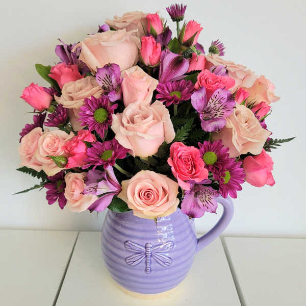 Pink and purple roses with daisies in a lavender pitcher vase