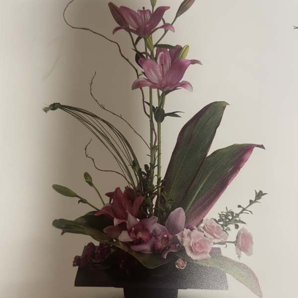 Tall floral arrangement with pink lilies and orchids in a black vase